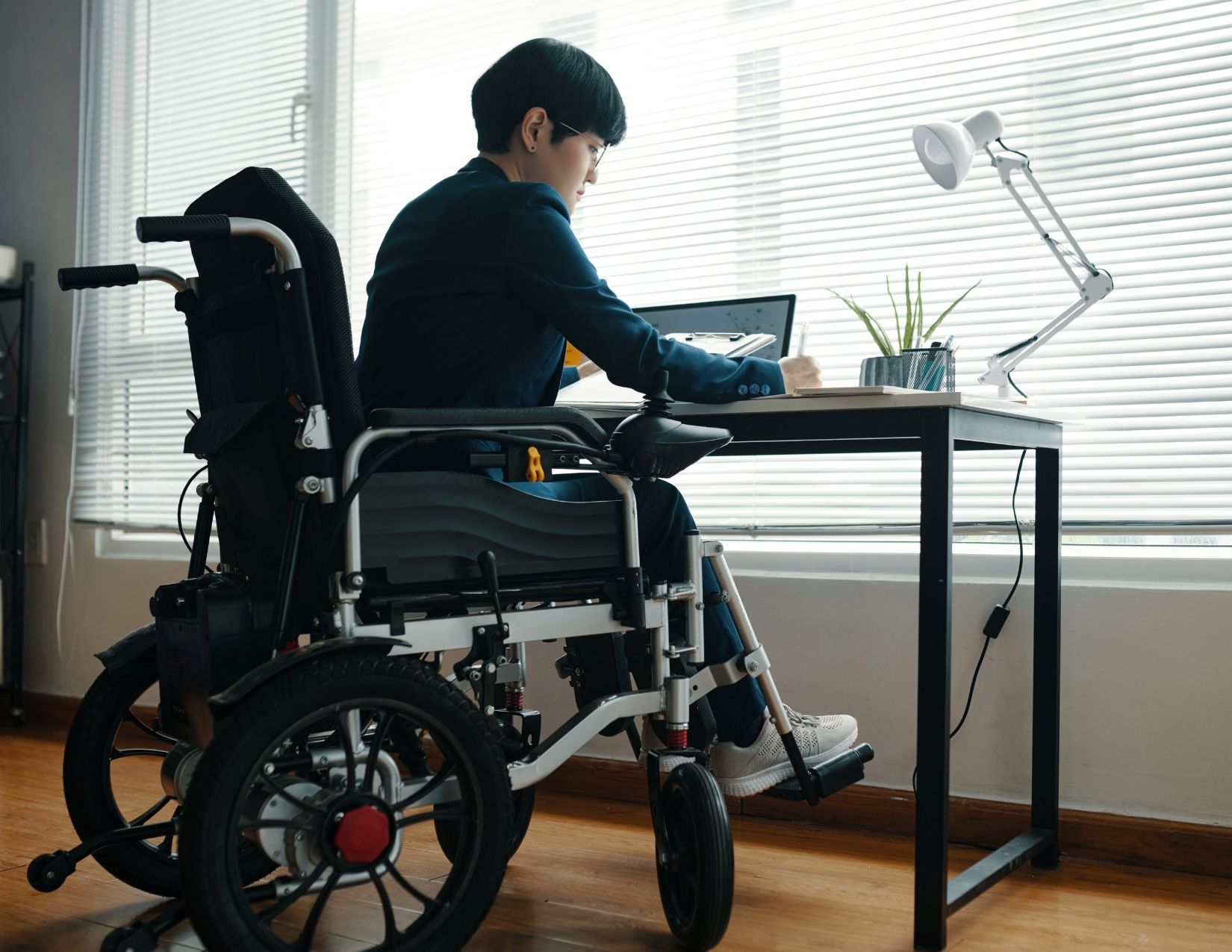 Young entrepreneur in wheelchair working at desk 